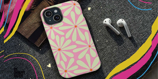 Stylish floral phone case with pink and green design next to wireless earphones.