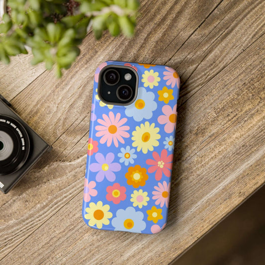 Colorful floral phone case on wooden table next to camera and potted plant.