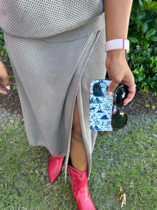 Stylish phone case with blue patterns, paired with a beige dress and red boots, held by a person with sunglasses and a smartwatch.