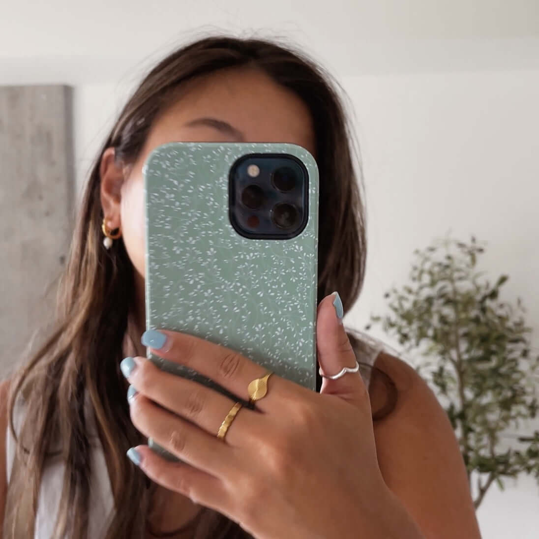 Person holding green dotted iPhone case displaying cute and protective phone accessory.