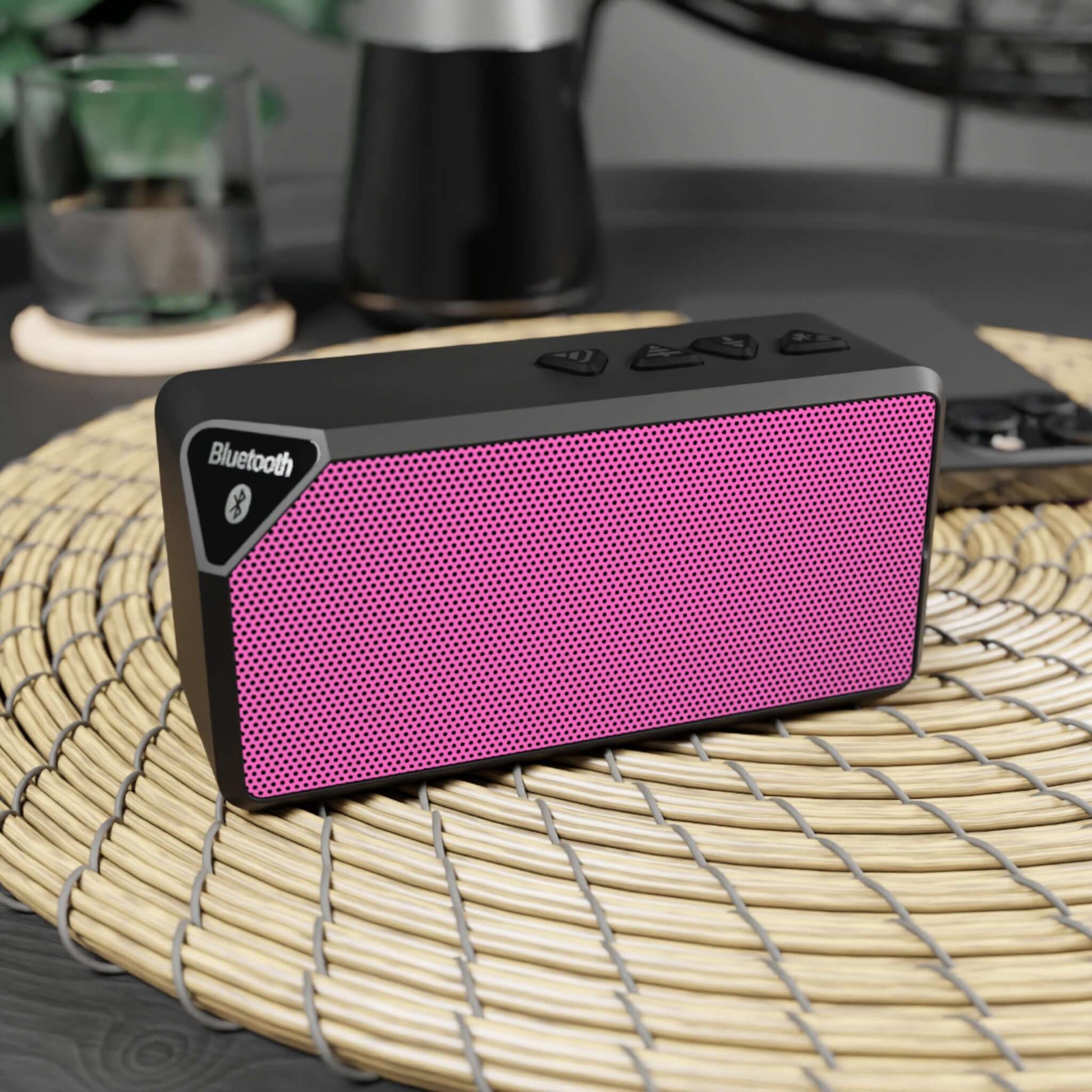 Pink Bluetooth speaker on a woven mat, ideal for parties, road trips, and holidays with 33-foot range and 2-hour playback.